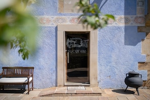 A building entrance with a bench, a door with a sign, and a pot on the ground. - Room 'Ablanu' with Mountain View, Shared Garden and Wi-Fi (Con)
