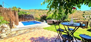 Un pati amb piscina, taula i cadires, i vista al camp.
