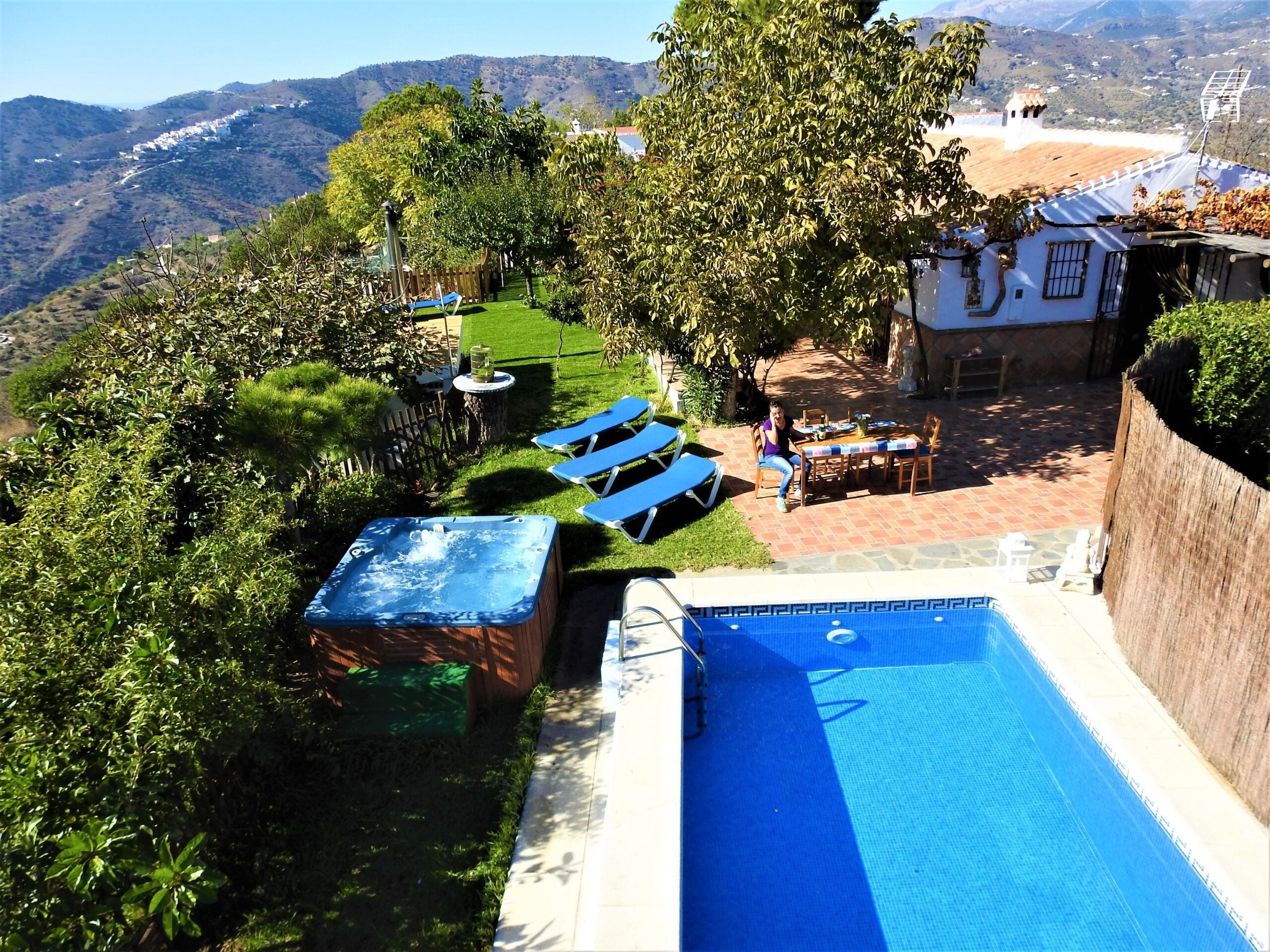 Un área de piscina con jacuzzi, sillas de descanso y una mesa con sillas.