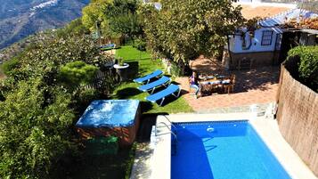 Un área de piscina con jacuzzi, sillas de descanso y una mesa con sillas.