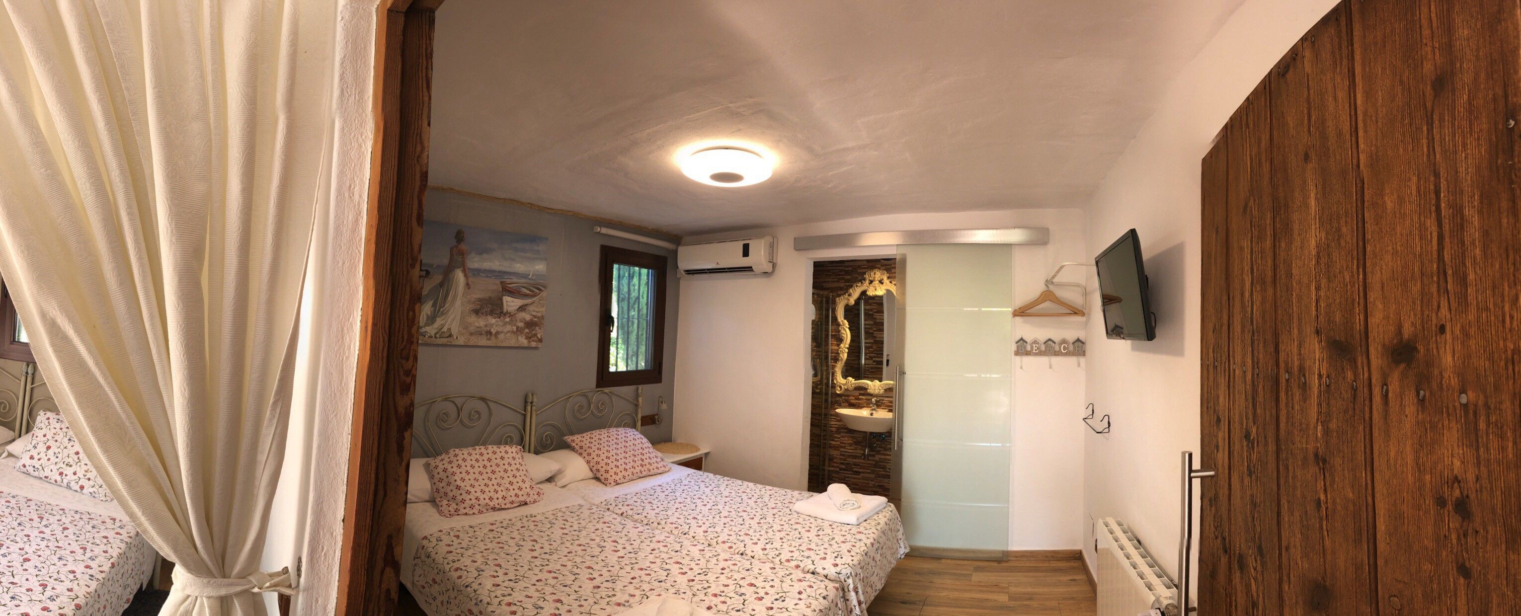 Un dormitorio con cama, ventana, aire acondicionado, espejo y puerta de madera.