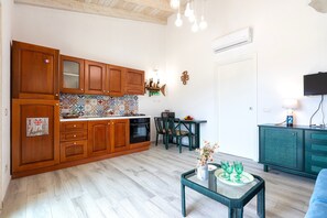 A kitchen with wooden cabinets, a tiled backsplash, and a dining area with chairs and a table.