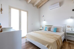 A bedroom with a bed, bedside tables, an air conditioner, a nightstand, and a window.