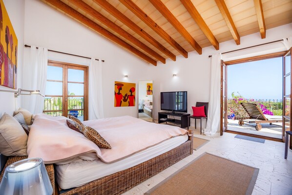 Une chambre à coucher avec un lit, une télévision et un balcon offrant une vue.
