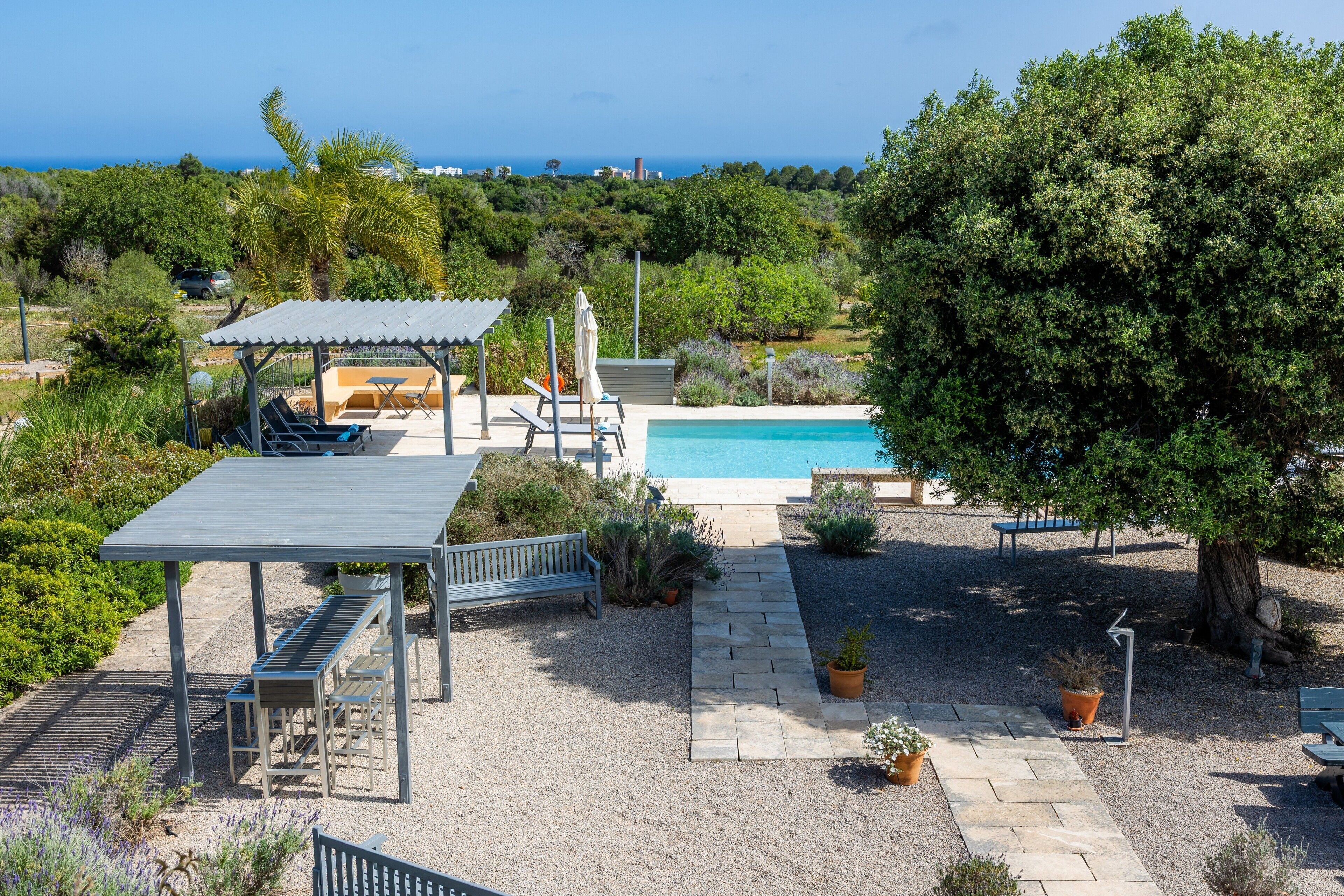 Un espace piscine doté d’un coin salon couvert, d’une pergola et d’une vue sur la mer.