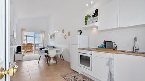 A modern kitchen with white cabinets, a stainless steel sink, and a wooden countertop.