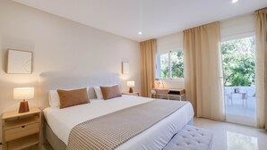 Une chambre avec un grand lit, des tables de chevet, un bureau et une vue sur l’extérieur.