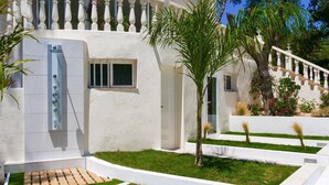 Un bâtiment moderne à l’extérieur blanc, doté d’une petite fenêtre et d’un escalier menant à un balcon.