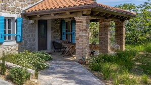 A stone building with a covered patio, a door, and a table with chairs. - Nice home in Mundanije with outdoor swimming pool (Mundanije)