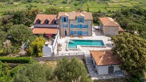 A large stone house with a swimming pool, surrounded by lush greenery and fields. - Nice home in Mundanije with outdoor swimming pool (Mundanije)