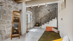 A spacious living area with a stone wall, a wooden bench, a staircase, and a sofa with cushions. - Nice home in Mundanije with outdoor swimming pool (Mundanije)