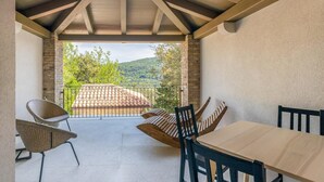 Un patio exterior con mesa y sillas, un muro de piedra y vistas a la montaña.