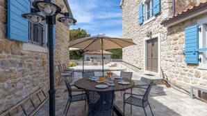 An outdoor dining area with a round table, chairs, and an umbrella. - Amazing home in Mundanije (Mundanije)