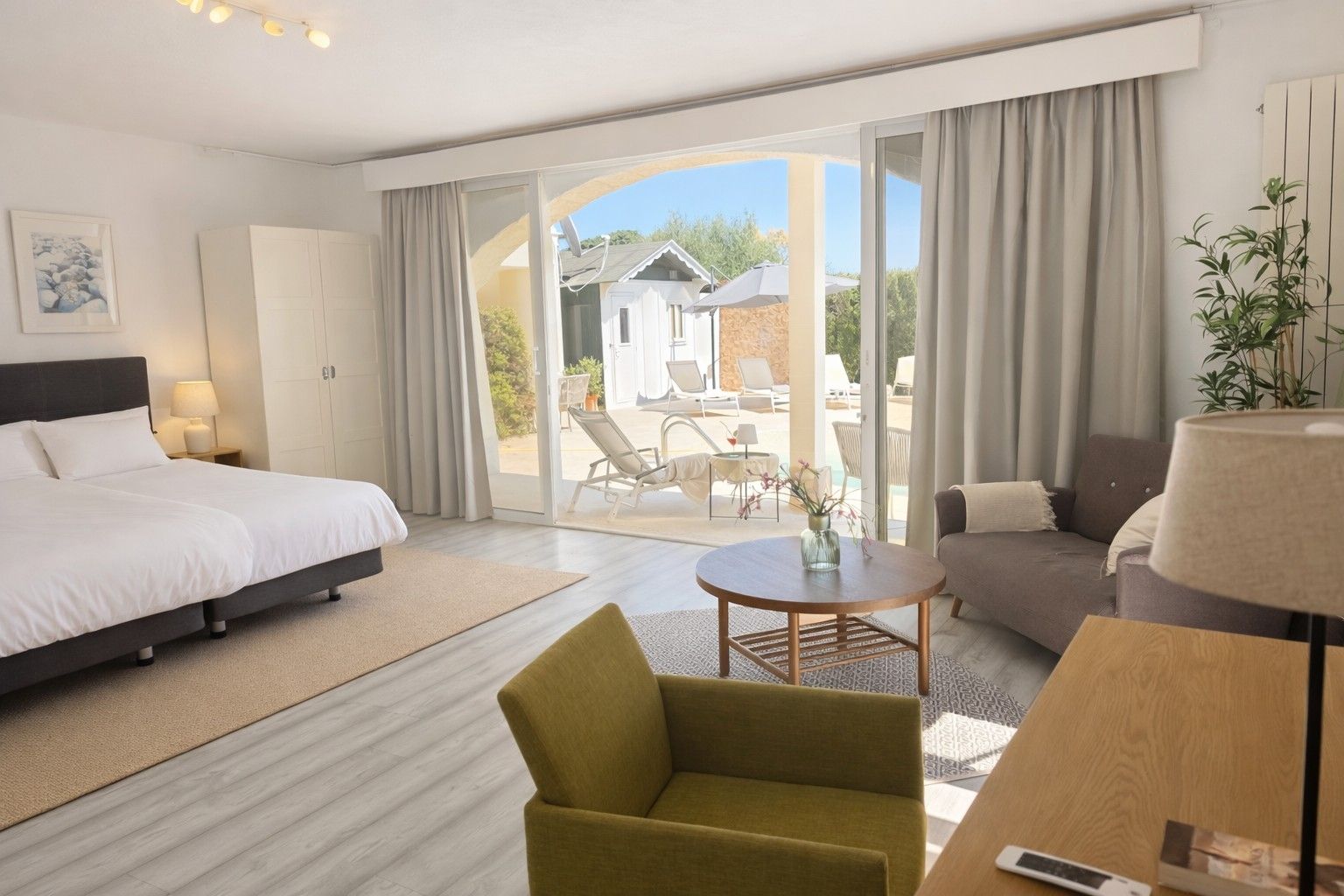 Een hotelkamer met een bed, een slaapbank, een stoel, een tafel en uitzicht op het buitengebied.