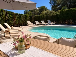 A poolside area with lounge chairs, a wooden table, and a potted plant. - Holiday Home 'Tres Palmeras' with Sea View, Wi-Fi and Air Conditioning (Cales de Mallorca)