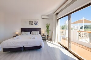 Una habitación de hotel moderna con una cama grande, un balcón con vistas y una ventana.
