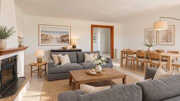 Un salon comprenant une cheminée, un canapé, une table basse et un coin repas avec des chaises et une table.