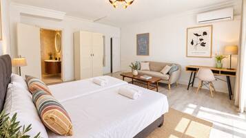 Ein Hotelzimmer mit einem großen Bett, einem Schreibtisch, einer Sitzecke und einem Badezimmer mit Spiegel und Schränken.