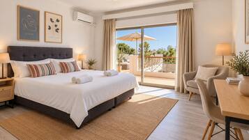 A hotel room with a large bed, a balcony with an umbrella, and a dining area.