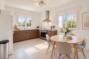 A modern kitchen with a built-in oven, microwave, and stove, wooden cabinets, and a dining area with a round table and chairs.