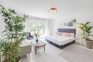A modern bedroom with a large bed, bedside tables, a desk, and potted plants. - Holiday Home 'Tres Palmeras' with Sea View, Wi-Fi and Air Conditioning (Cales de Mallorca)