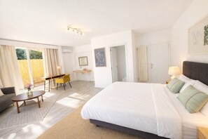 A hotel room with a large bed, a desk, a chair, and a view of the outdoors.