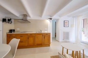 A modern kitchen with wooden cabinets, a white countertop, and a dining area with a white table and chairs.