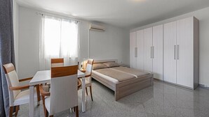 A modern bedroom with a bed, a desk, chairs, and a wardrobe.