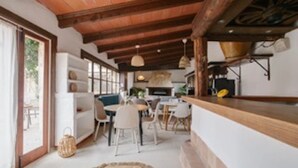 Amplia sala de estar con techo de madera, una mesa de comedor y una zona de cocina con estufa.