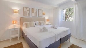 Un dormitorio con una cama grande, dos mesitas de noche y una ventana con cortinas.