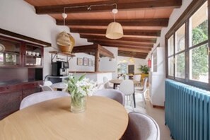 A dining area with a round table, chairs, a vase with flowers, and a ceiling with exposed beams. - Holiday Home 'Marilla I' with Communal Pool, Wi-Fi, and Air Conditioning (Manacor)