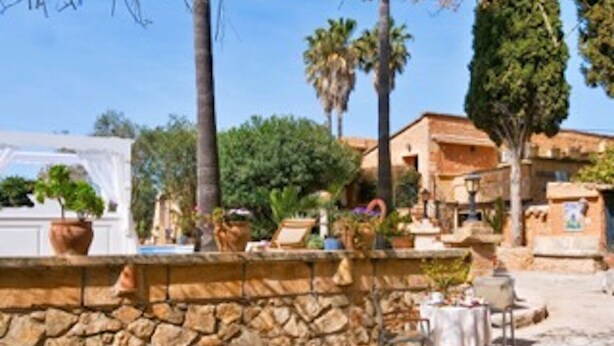 A stone wall, outdoor seating, and a building with a tiled roof.
