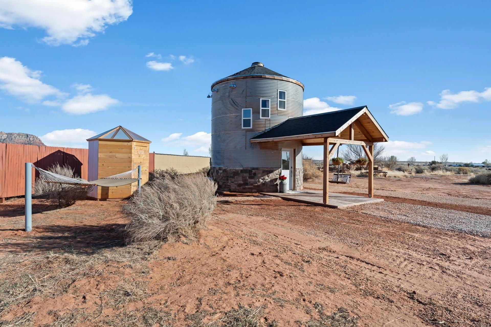 A rustic cabin with a water tower, a wooden structure, and a covered outdoor seating area.