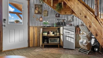 Eine rustikale Küche mit Holzbalkendecke, einem Kühlschrank und einer Mikrowelle.