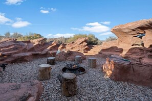 A rocky outdoor area with wooden stumps and a fire pit.