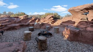 A natural rock formation with a fire pit surrounded by wooden stumps and gravel. - Southwest Silo Stay- 1 Bedroom Near Zion & Bryce (Fredonia)