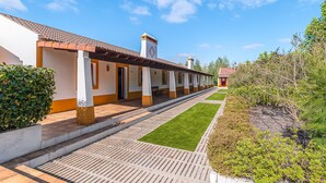 Een hotel met een lange gang, aparte kamers en een kleine tuin.