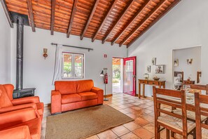 A spacious living area with a fireplace, orange sofa, wooden dining table, and chairs.