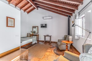 Una habitación con techo de madera, una cama, un televisor, una mesita y una silla.