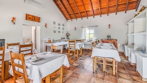 A dining area with multiple tables, wooden chairs, white tablecloths, and a tiled floor. - Apartment 'Casa Ti Herminia - Suite Deluxe' with Shared Pool, Wi-Fi and Air Conditioning (Carvalhal)