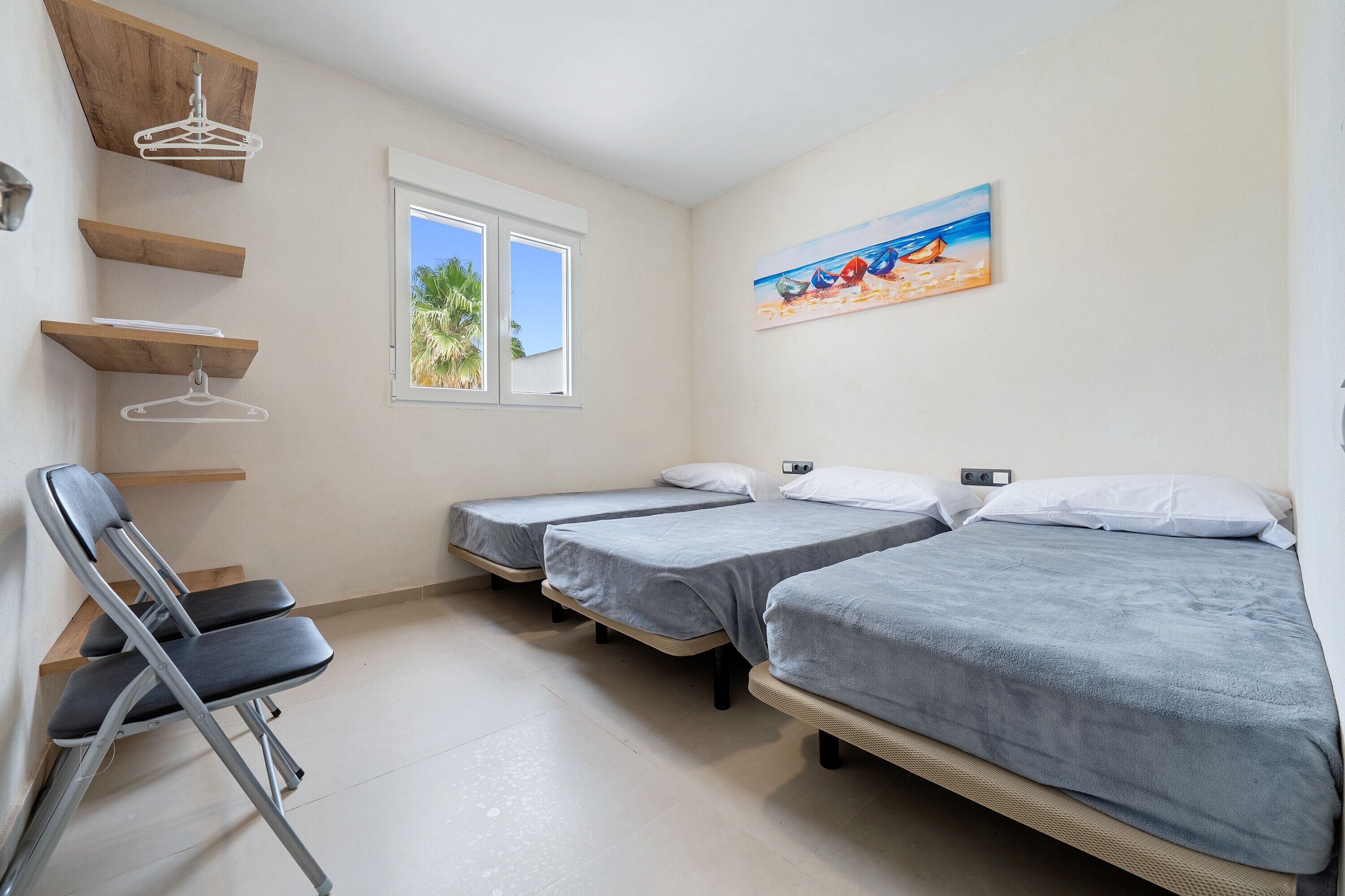 A room with three beds, a chair, and a window.