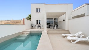 Un edificio moderno con piscina, zona de estar exterior y cielo despejado.
