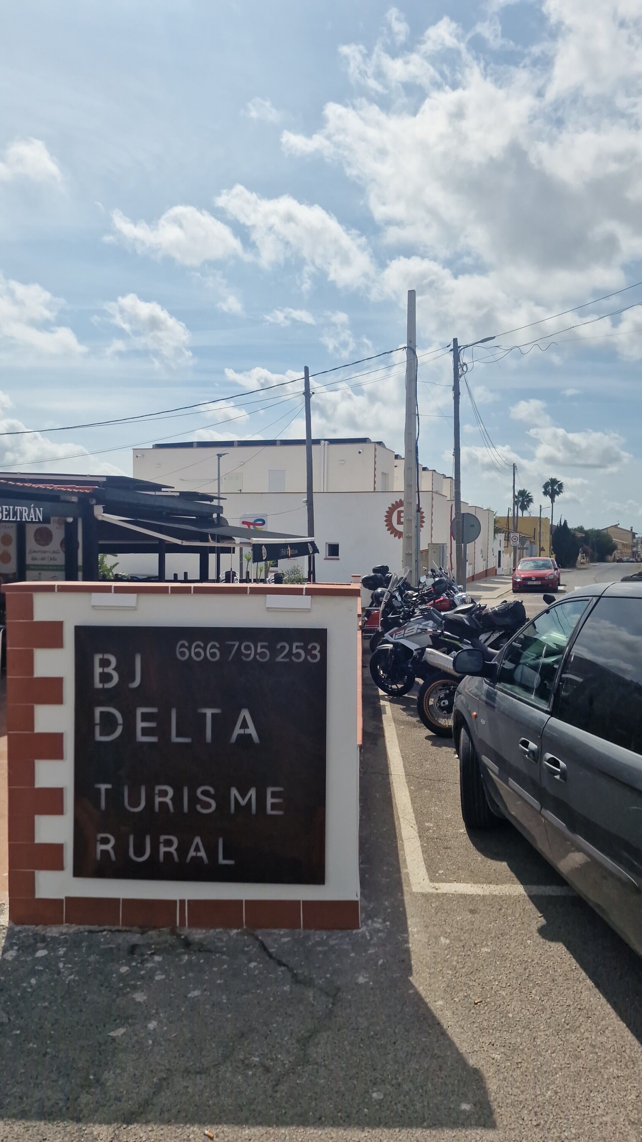 Señalización para 'BJ DELTA TURISME RURAL' con zona de estacionamiento y motocicletas.