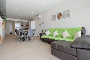 A modern living room with a dining area, grey sofas, and a green couch. - Holiday Home 'Illa De Buda' with Mountain View, Wi-Fi and Air Conditioning (Camarles)
