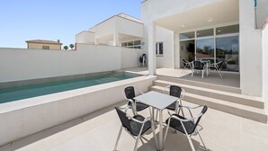 Une terrasse extérieure moderne, dotée d’une piscine, de coins salon et offrant une vue sur les environs.