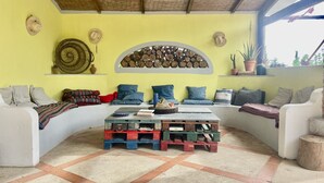 A cozy seating area with a bench, cushions, and a wall decorated with hats and a wood log display.