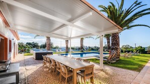 Un espace extérieur abrité comprenant une piscine, une table à manger avec des chaises et des fauteuils de relaxation.