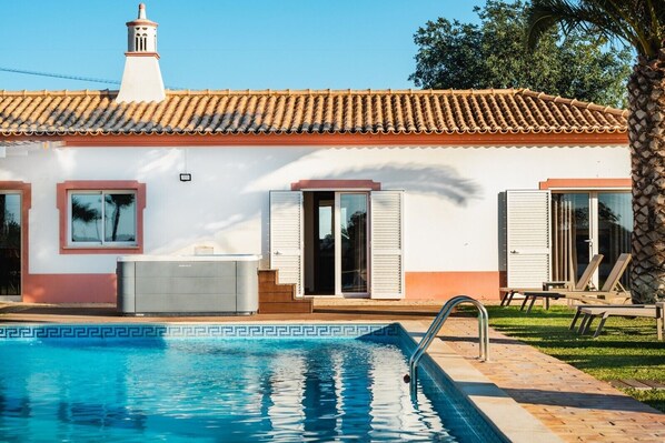 A house with a swimming pool, a hot tub, and a palm tree.