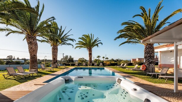 Une piscine avec des chaises longues, un jacuzzi et des palmiers.