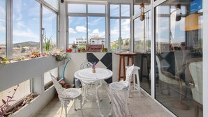 A sunlit balcony with a table and chairs, potted plants, and a view of the cityscape. - Room 'Duplo Superior' with Balcony, Wi-Fi and Air Conditioning (São Brás de Alportel)
